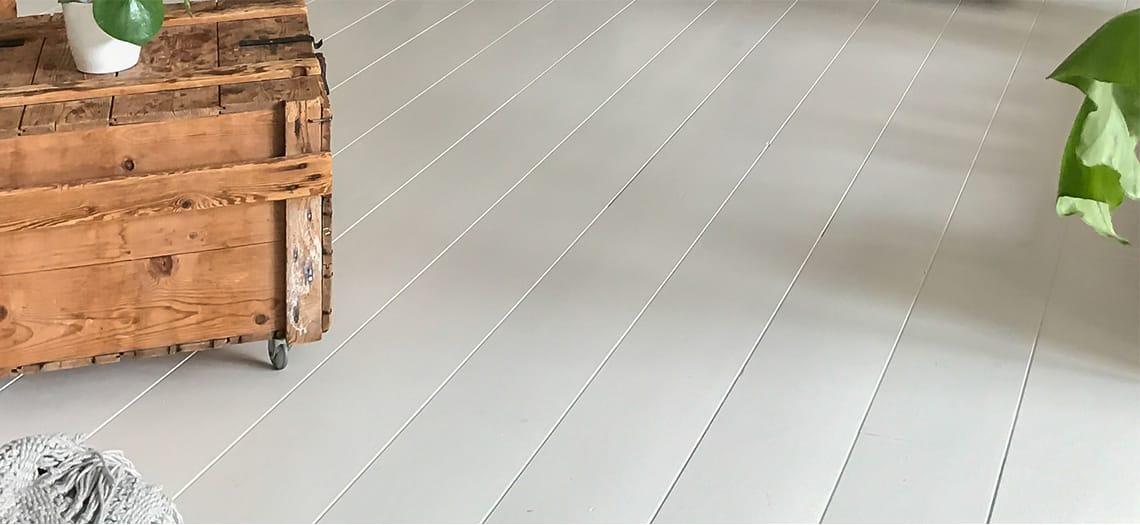 Wit geverfde plankenvloer met een oude houten kist