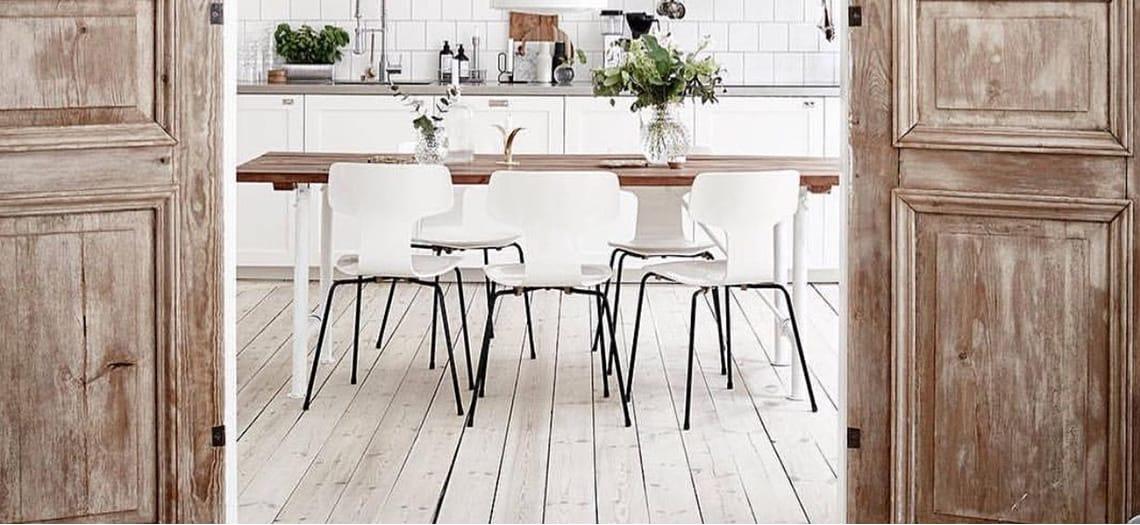 Witgeschuurde plankenvloer met een eettafel en oude houten deuren