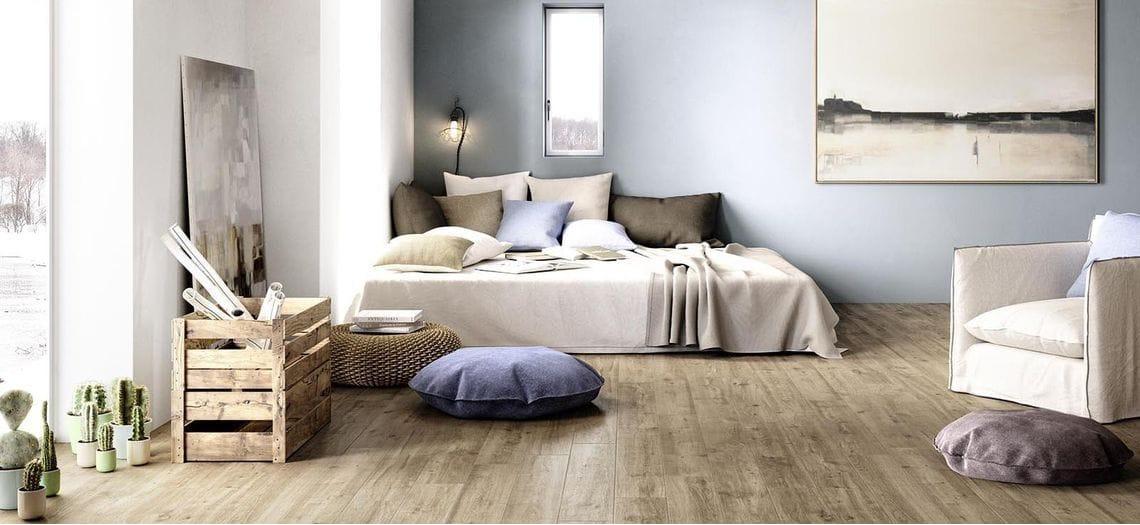 Slaapkamer met een lichte houten vloer en een opgemaakt bed