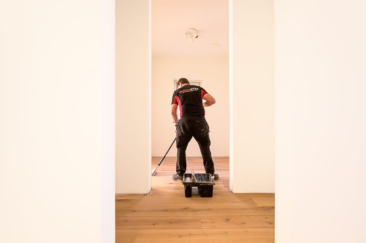 Woodstep-medewerker lakt een vloer met een roller