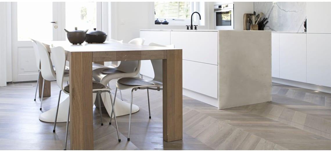 Witte keuken met een lichte visgraatvloer en een eettafel