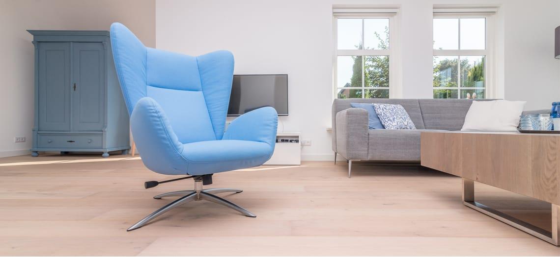 Modern interieur met een lichtblauwe fauteuil op een lichte vloer