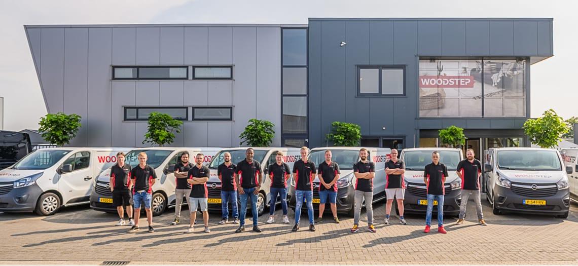 Het team van Woodstep voor het bedrijfspand, met de bedrijfsbussen