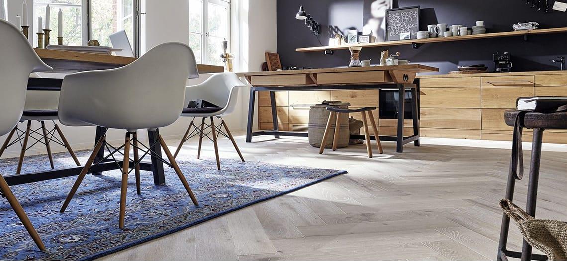 Lichte eethoek met witte stoelen en een blauw vloerkleed op een lichte vloer