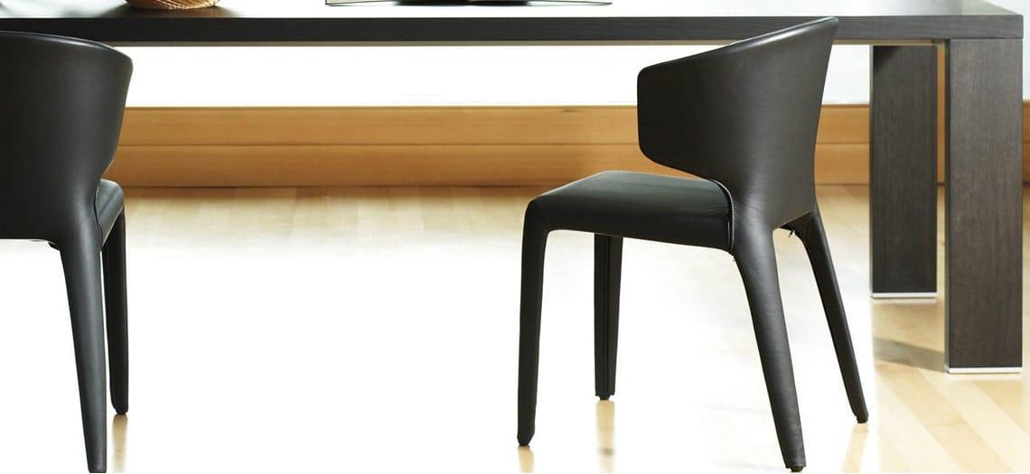 Zwarte stoelen aan een tafel op een lichte houten vloer