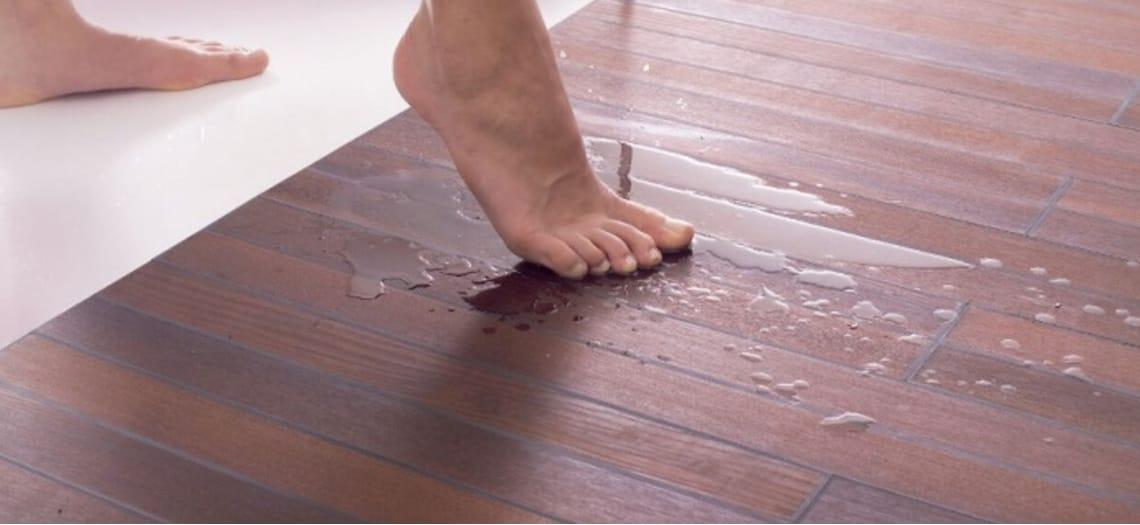 Blote voet in een plas water op een houten vloer