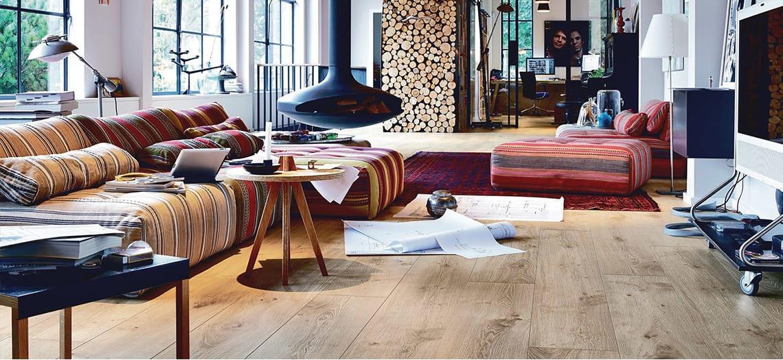 Woonkamer met een brede eiken vloer, haard en kleurrijke banken