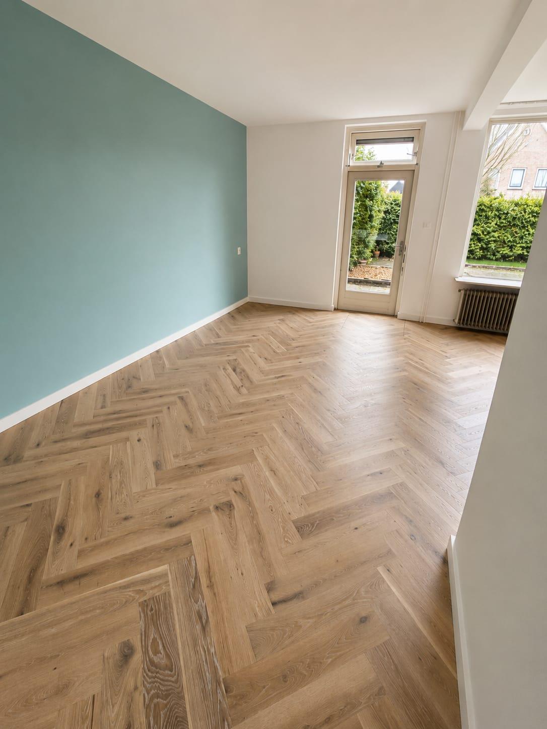 Eiken visgraatvloer in een kamer met een groenblauwe muur