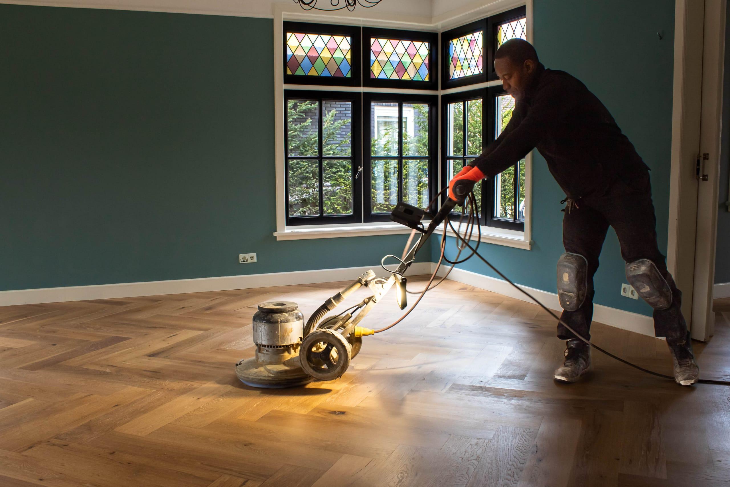 Woodstep-medewerker polijst een eiken visgraatvloer